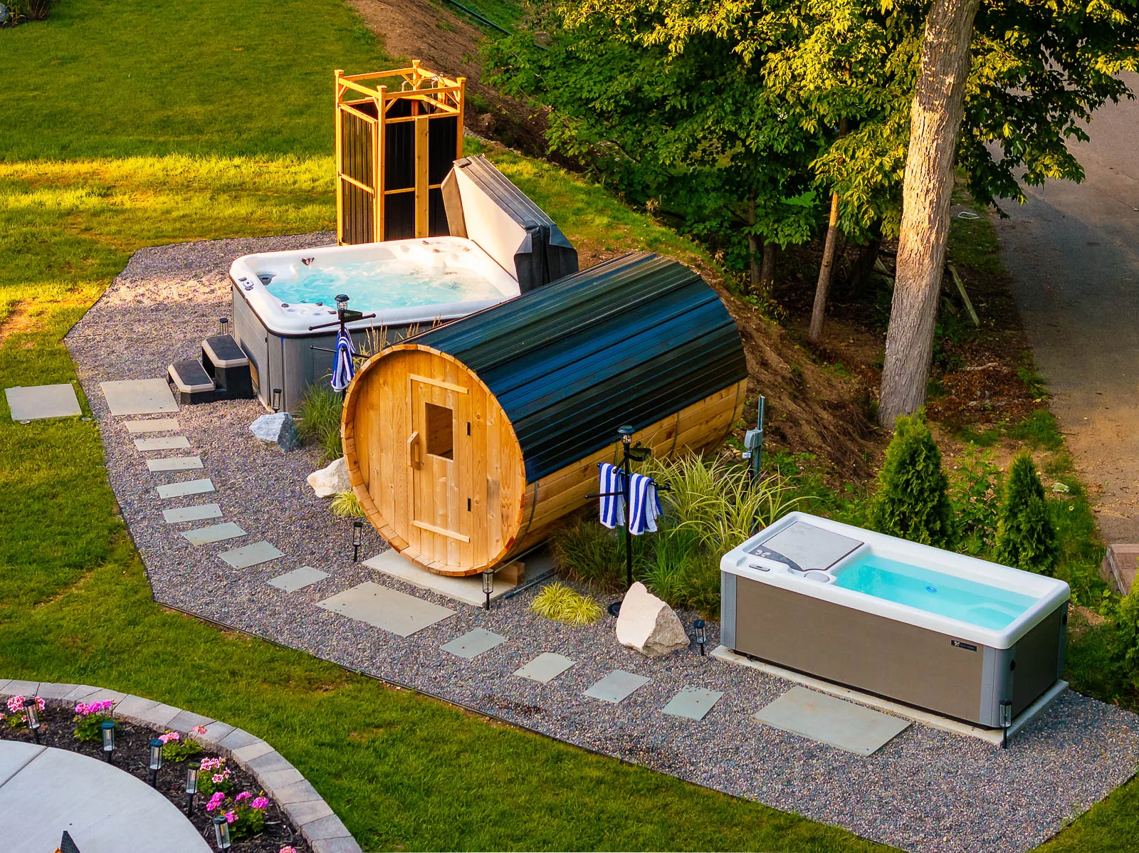Outdoor wellness area with hot tub, barrel sauna, and cold plunge