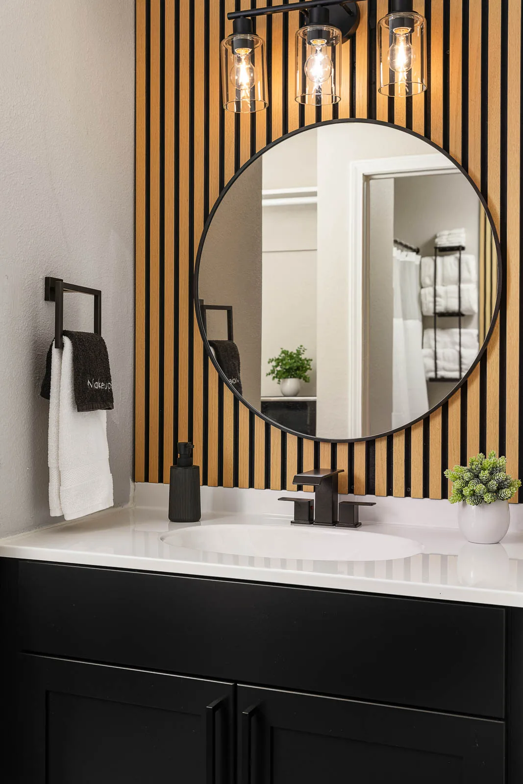 King Lodge Suite bathroom vanity with round mirror and wood detail wall