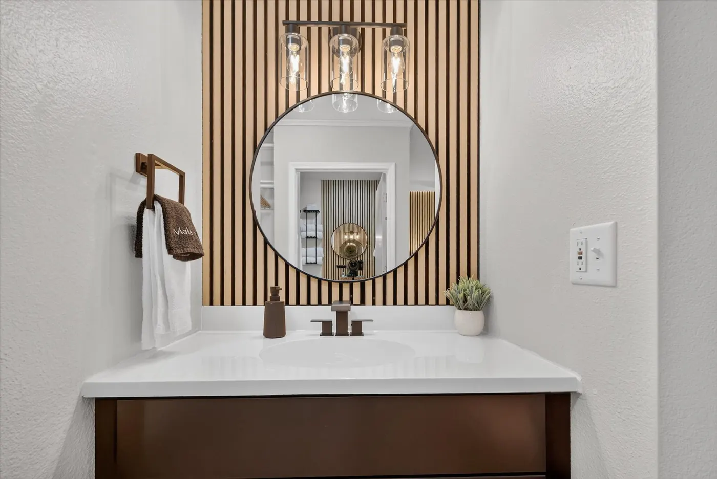Updated bathroom vanity with round mirror and wood accent wall