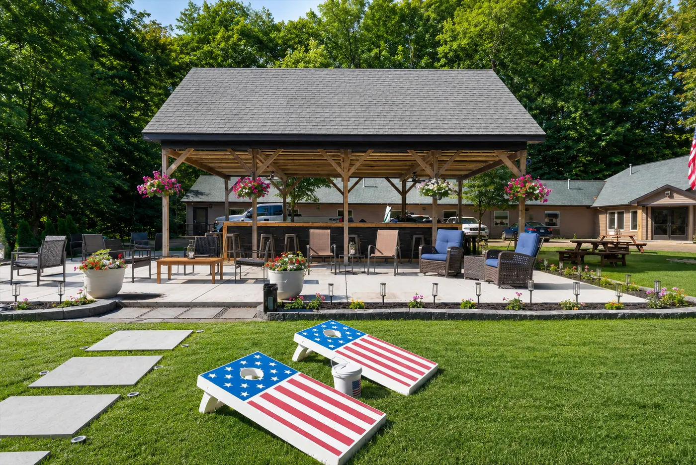 Outdoor pavilion with seating, lawn games, and cornhole boards