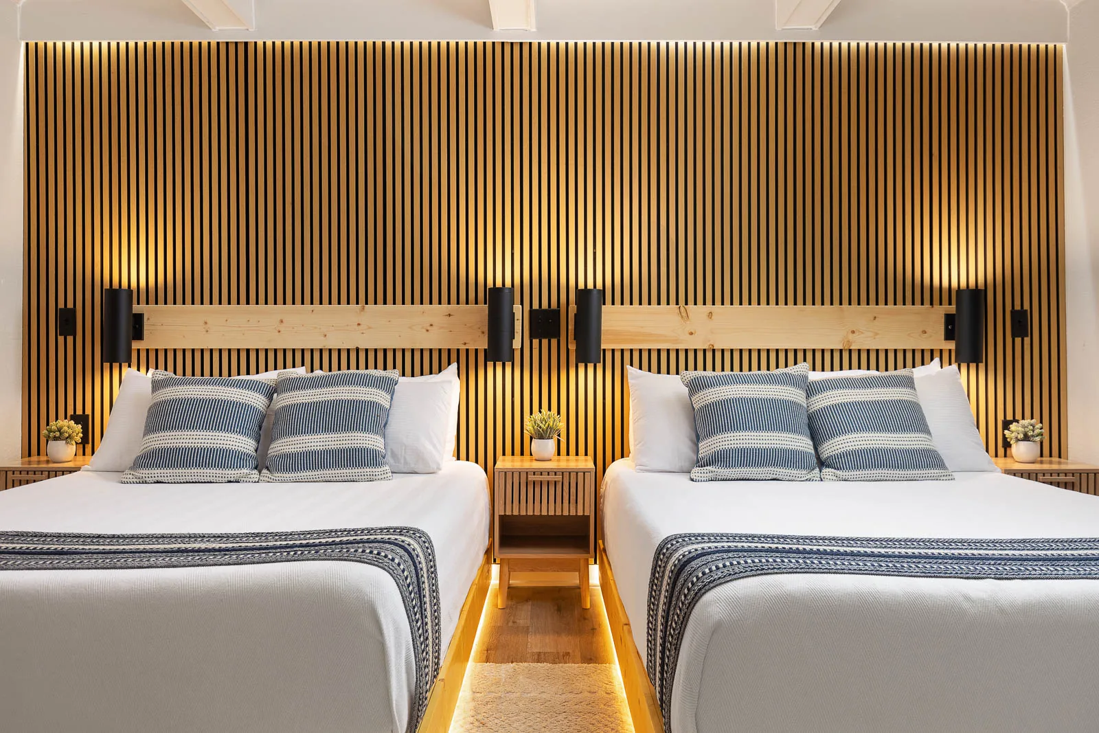 Front view of two queen beds and bedside lighting