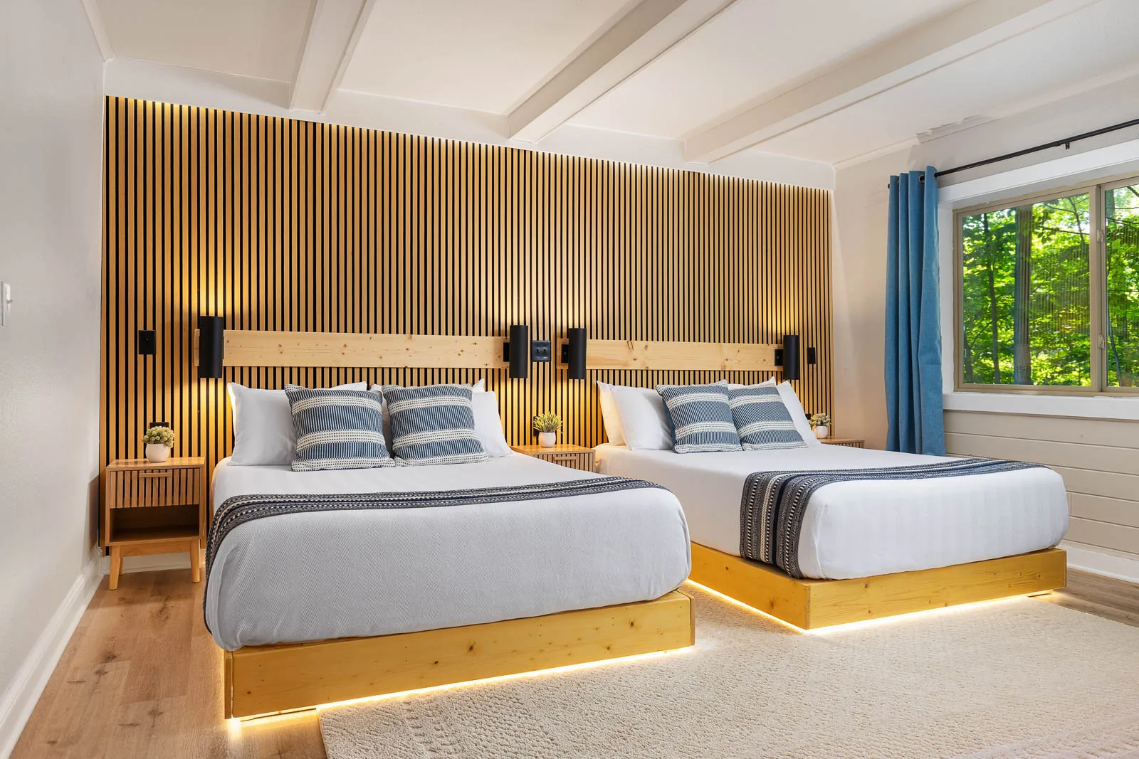 Two queen beds with warm wood accent wall